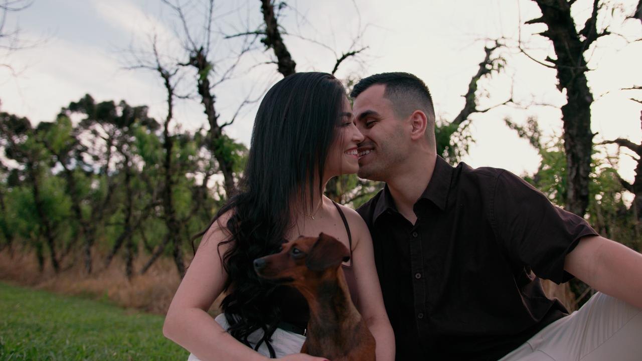 O casal sentado na grama com o cachorro