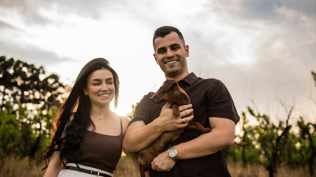 Juliana e Matheus sorrindo com o cachorrinho no colo