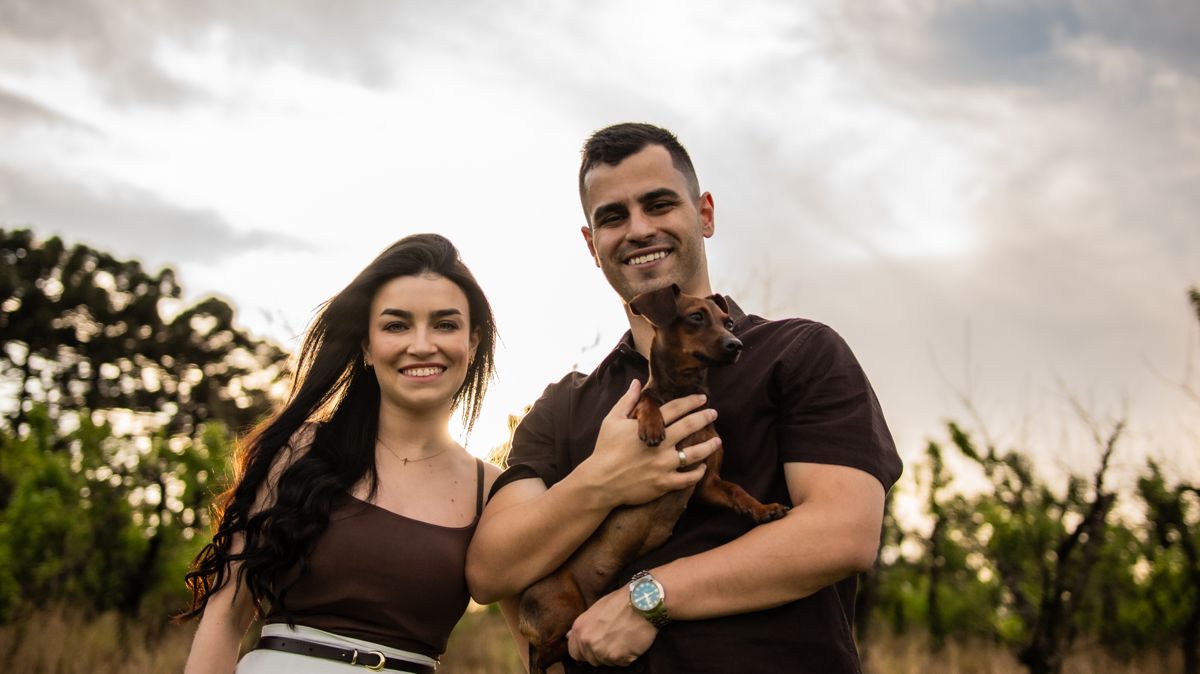 Juliana e Matheus sorrindo com o cachorrinho no colo