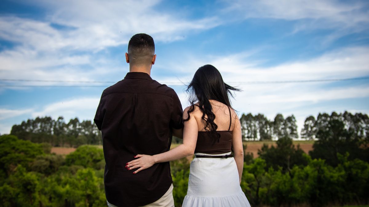 O casal abraçado, de costas, olhando o campo