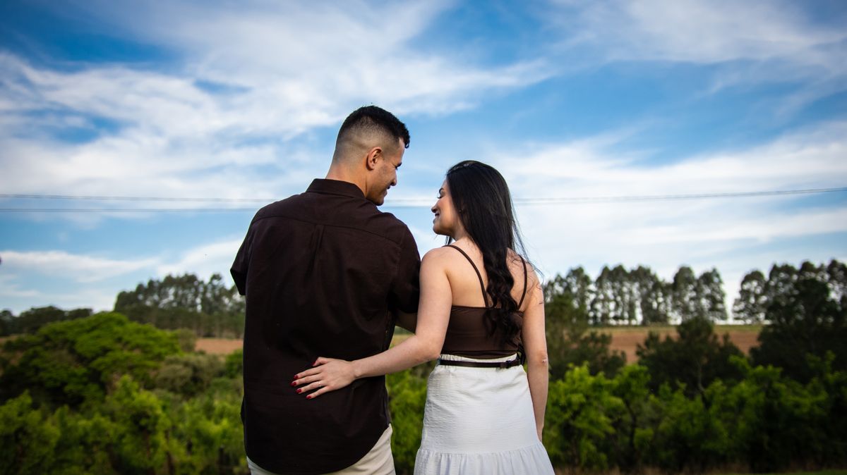 O casal abraçado, de costas, olhando o campo