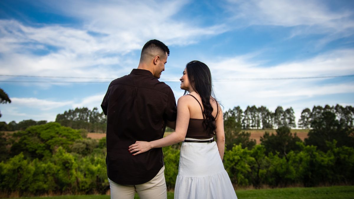 O casal abraçado, de costas, olhando o campo